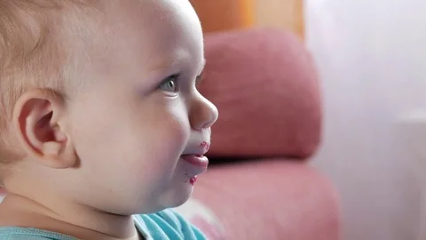 An attractive boy 2 years old eats a red beet salad. The face is smeared with Stock Footage 73839464