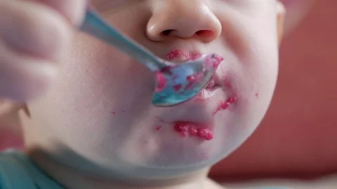 An attractive boy 2 years old eats a red beet salad. The face is smeared with Stock Footage 73839690