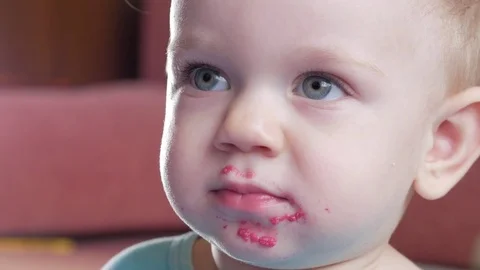 An attractive boy 2 years old eats a red beet salad. The face is smeared with Stock Footage 73839997