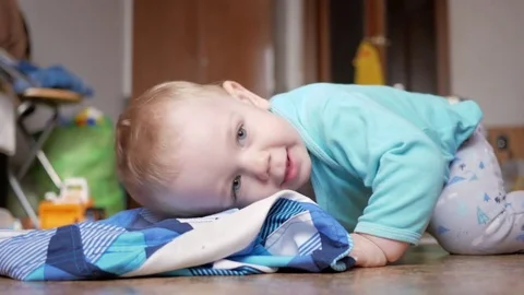 An attractive boy 2 years old is lying on the floor on clothes. He rests after Stock Footage 73841644