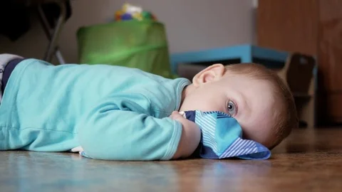 An attractive boy 2 years old is lying on the floor on clothes. He rests after Stock Footage 73841743