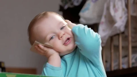 An attractive boy 2 years old picks up a big puzzle. He takes and looks at the Stock Footage 73842549