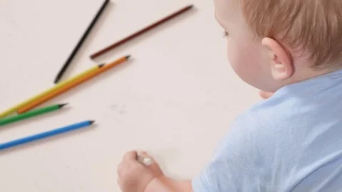 An attractive boy 2 years old draws in colorful pencils at home. It is black in Stock Footage 73963958