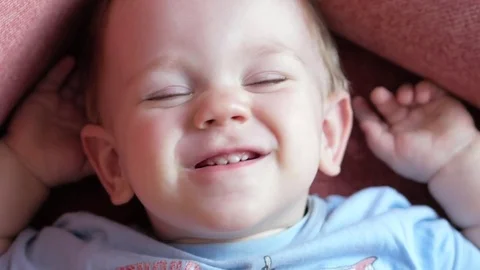 An attractive boy 2 years old is looking at the cameras and playing facial Stock Footage 73964655