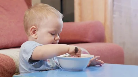 An attractive boy 2 years old is eating red soup himself. Spoon and hands Stock Footage 73966117