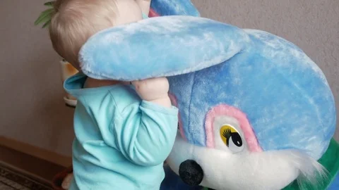 An attractive boy 2 years old plays with a huge plush rabbit at home. Kid shows Stock Footage 74710727