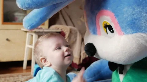 An attractive boy 2 years old plays with a huge plush rabbit at home. Kid shows Stock Footage 74711244