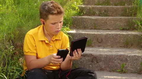 Attractive boy passionately playing with gadgets outdoors. Stock Footage 169063997