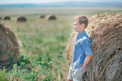 Attractive boy sitting on a haystack and smiling Foto stock