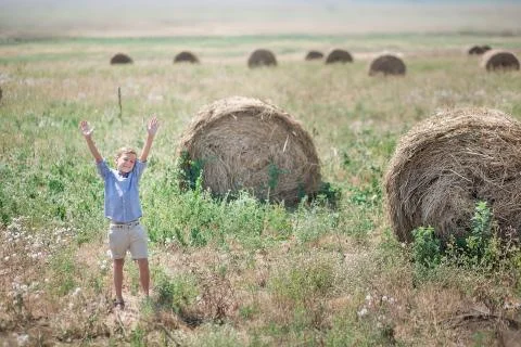 Attractive boy sitting on a haystack and smiling Stock Photos