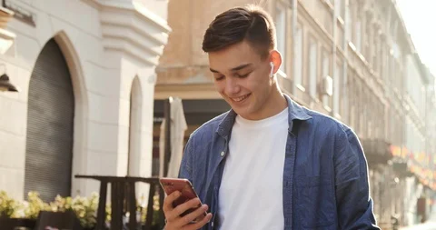 Attractive Boy smiling while using and browsing his modern Smartphone.  Stock Footage 112156731