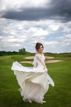 Attractive bride dancing and smiling on green golf course Stock Photos