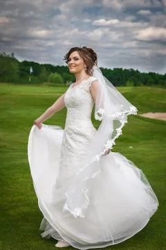 Attractive bride dancing and smiling in green nature Stock Photos