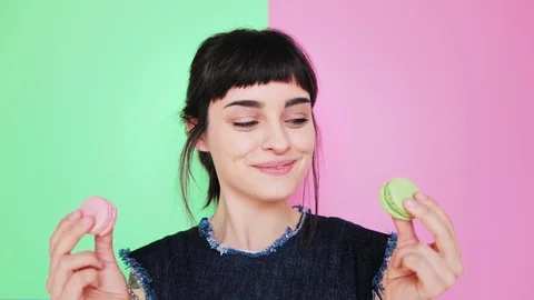 Attractive brunette eats macarons isolated on bright backgrounds Stock-Footage 73295020