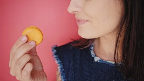 Attractive brunette eats macarons isolated on bright backgrounds Video stock 73299202