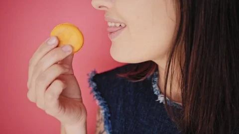 Attractive brunette eats macarons isolated on bright backgrounds Video stock 73299657