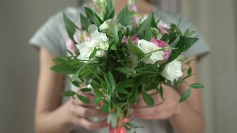 Attractive brunette florist holds out a bouquet of flowers in front close-up 4k. Stock Footage 80351453