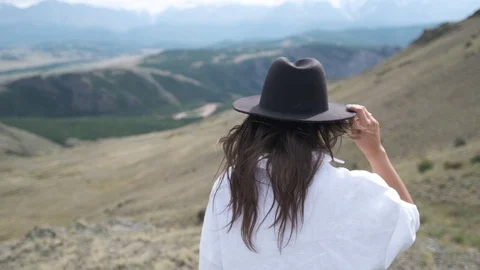 Attractive brunette in a hat and white shirt is enjoying nature in the mountains Stock Footage 118890697