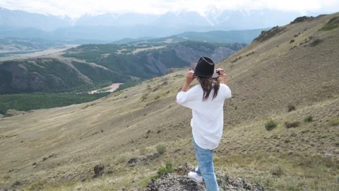 Attractive brunette in a hat and white shirt is enjoying nature in the mountains Stock Footage 118890727