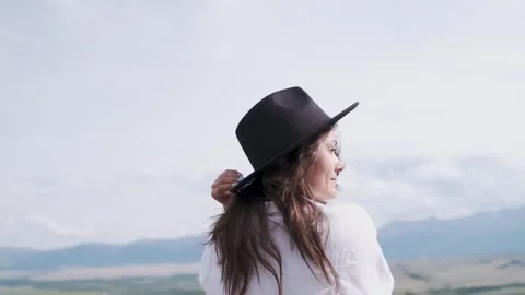 Attractive brunette in a hat and white shirt is enjoying nature in the mountains Stockbeeldmateriaal 131282102