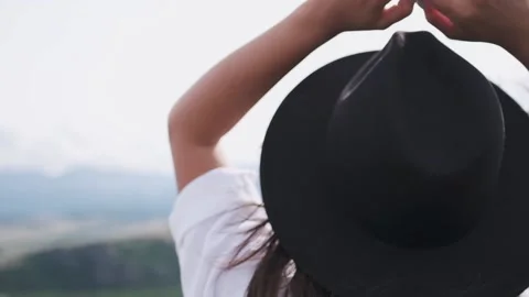 Attractive brunette in a hat and white shirt is enjoying nature in the mountains 库存影片 131431027