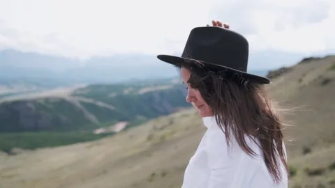 Attractive brunette in a hat and white shirt is enjoying nature in the mountains Vidéo 133038172