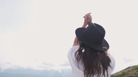 Attractive brunette in a hat and white shirt is enjoying nature in the mountains Stock Footage 133038385