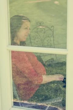 Attractive brunette looking through a window Stock Photos