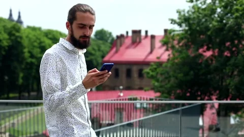 Attractive brunette man using smartphone outside calling friends smiling reading Video stock 135042958