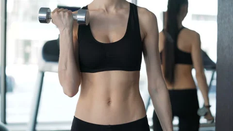 Attractive brunette with slender physique doing exercises using dumbbells. One r Video stock 199490582