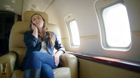 Attractive brunette using cellphone in comfortable seat on private jet 4K Stock Footage 53293601