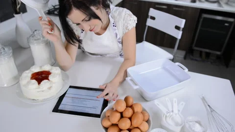 Attractive brunette woman using tablet computer while backing Stockbeeldmateriaal 199628924