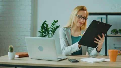 Attractive business woman checking the financial report siting on the table in Stock Footage
