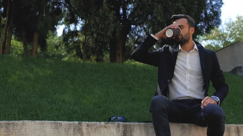 Attractive businessman with a beard drinks tea or coffee from a disposable cup Stock Footage 113903805