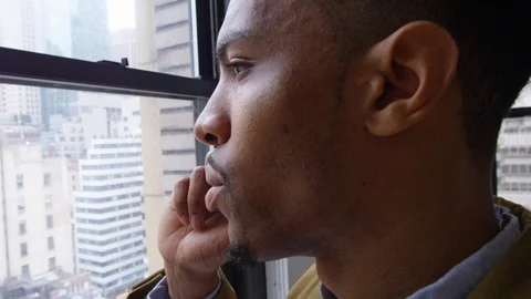 Attractive businessman looking through window while talking on the phone Stock Footage 93530202