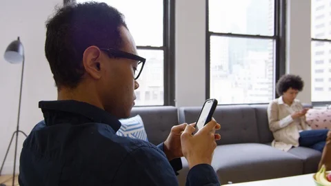 Attractive businessman using phone while his colleagues sitting at distance in 스톡 동영상 93531214