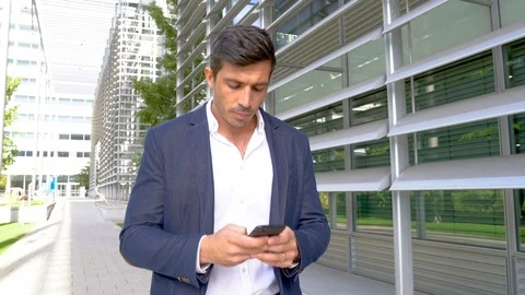 Attractive businessman walking and using phone app 4K Stock Footage 96048868