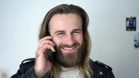 Attractive  caucasian man in leather jacket is talking on smartphone smiling Stock Footage 147898643