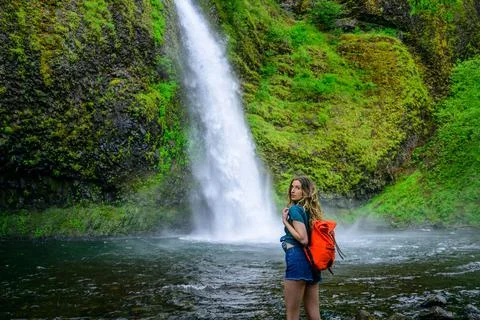 Attractive Caucasian woman standing against the Multnomah Falls in Oregon, Portl Stock Photos