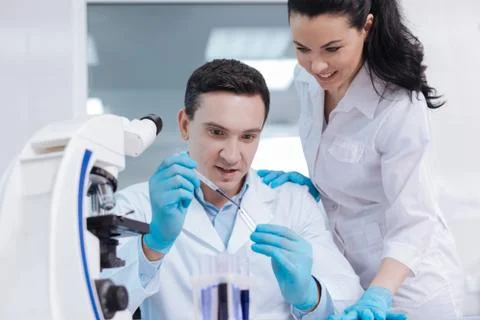Attractive competent lab assistant standing near her colleague Stock Photos