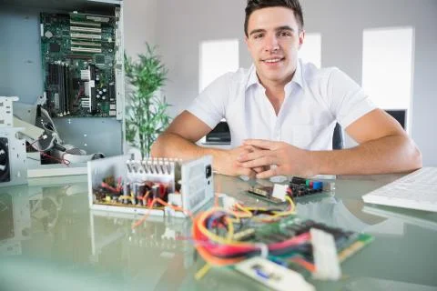 Attractive computer engineer sitting at desk smiling at camera Stock Photos