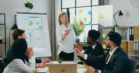 Attractive confident 45-aged blond female leader holding presentation for her Stock Footage 159657768