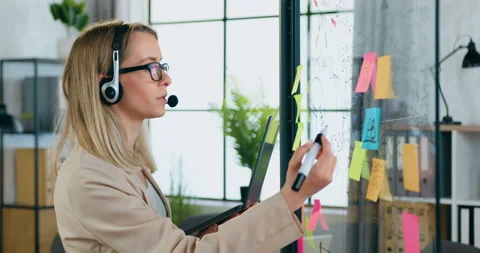Attractive confident experienced modern blond woman in headphones holding online Stock Footage 158005791