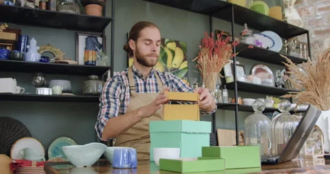 Attractive confident hardworking young bearded man packing gift boxes during Stock Footage 143971536