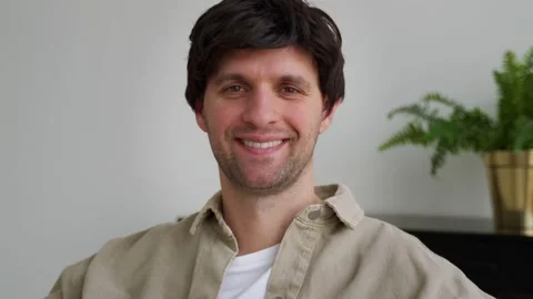 An attractive confident man looking into the camera, sitting in a modern living Stock Footage 188921921