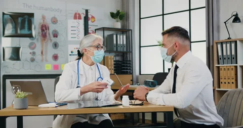 Attractive confident qualifed grey-haired female doctor in facemask checking Stock Footage 160822256