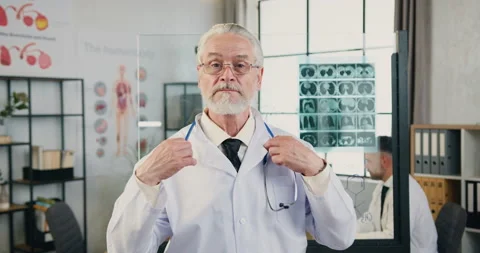 Attractive confident respected qualified senior bearded doctor putting on his Stock Footage 160421089