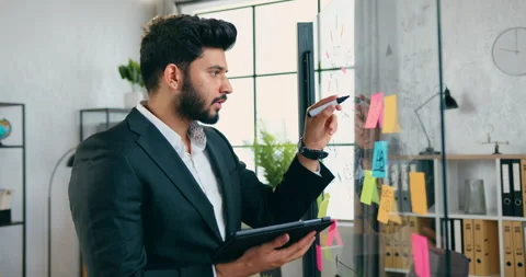 Attractive confident wise successful bearded worker working on glass wall and Stock Footage 157990630