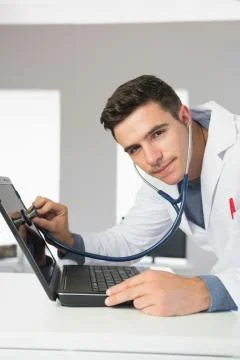 Attractive content computer engineer examining laptop with stethoscope Stock Photos