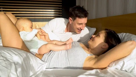 An attractive couple in a bed playing with their adorable baby boy Stock Footage 124869171